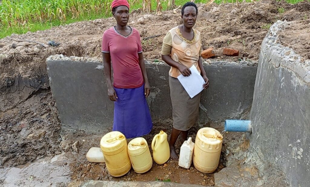 Two people collecting water from the newly constructed well