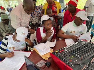 Staff writing records in books and operating audio equipment