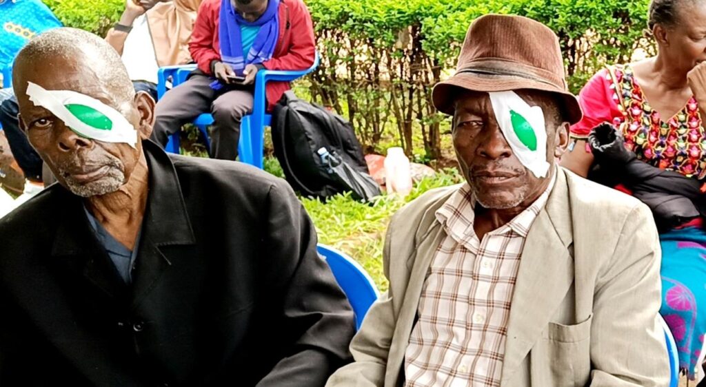 Two patients, each with an eye covered, having just received cataract surgery to restore sight